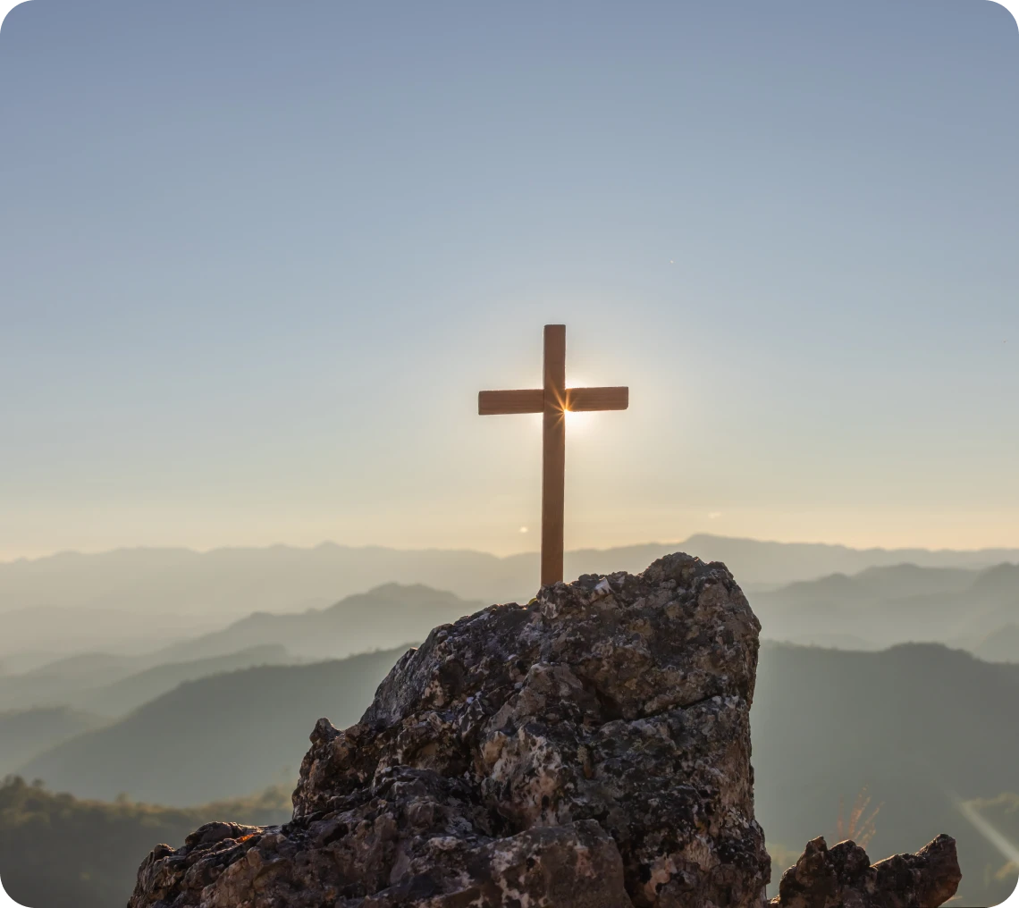 Wooden cross silhouetted by sunrise